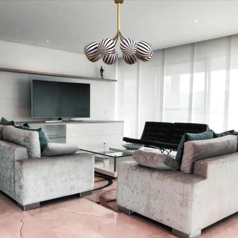 Modern living room with gray sofas, a glass coffee table, and a striped pendant light.