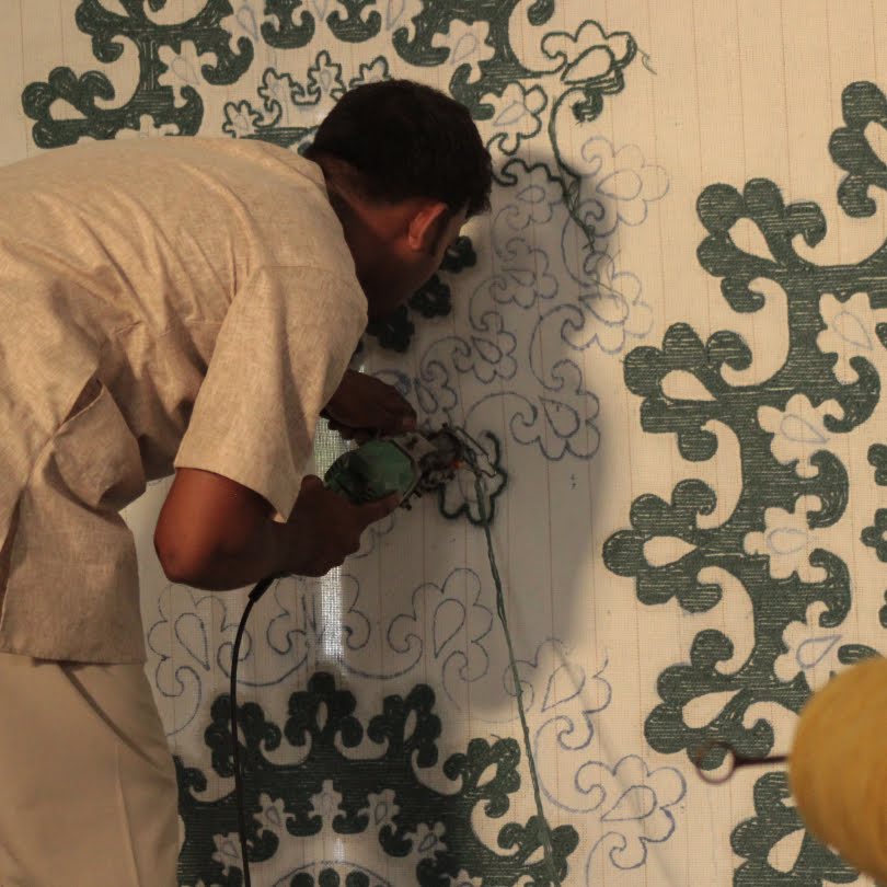 Hands dipping yarn into a vat of natural dye, illustrating the use of plant-based colors in carpet making.