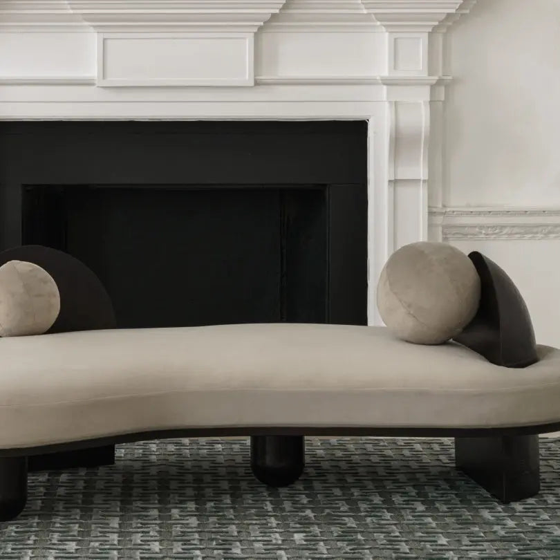 Liminal curved sofa by Atelier Ashiesh Shah, placed in front of a black fireplace.
