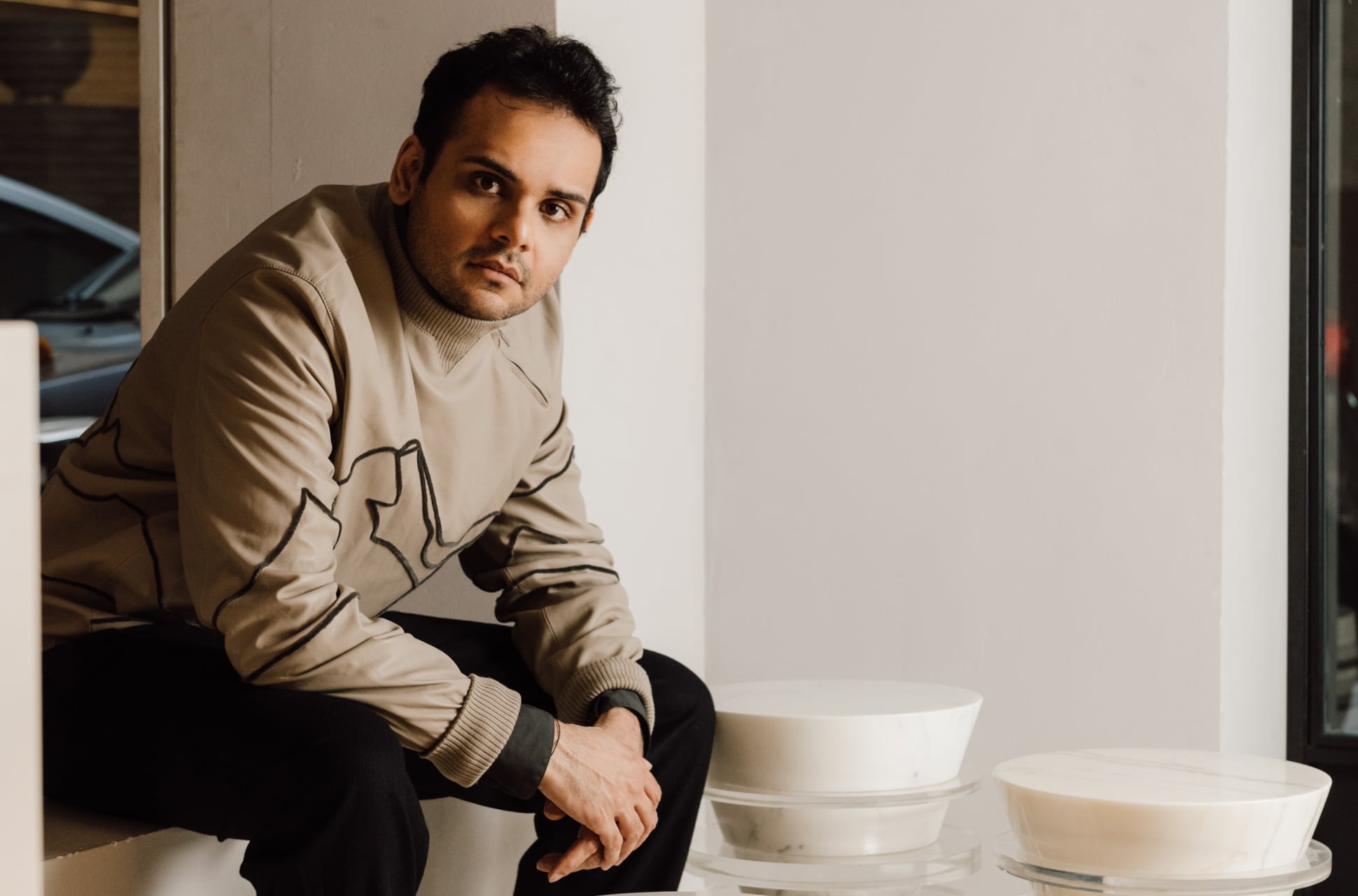 Portrait of Ashiesh Shah seated beside his modern sculptural designs.