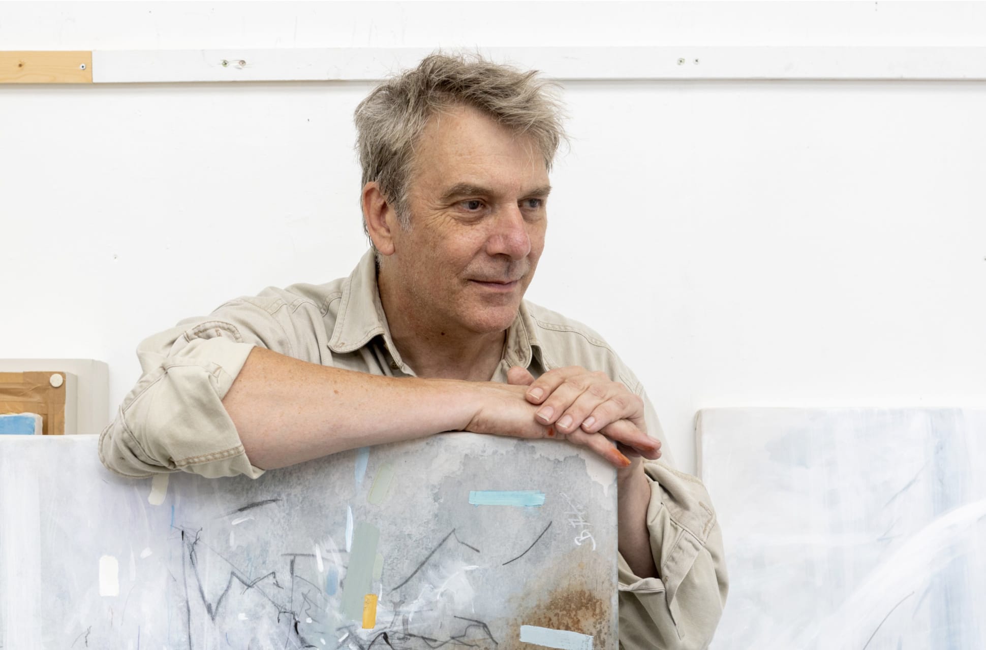 Artist Bob Aldous leaning on one of his abstract paintings.