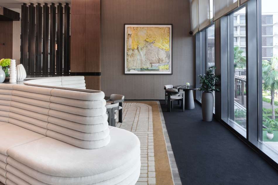 Modern interior with a white sofa, framed artwork, and large windows.