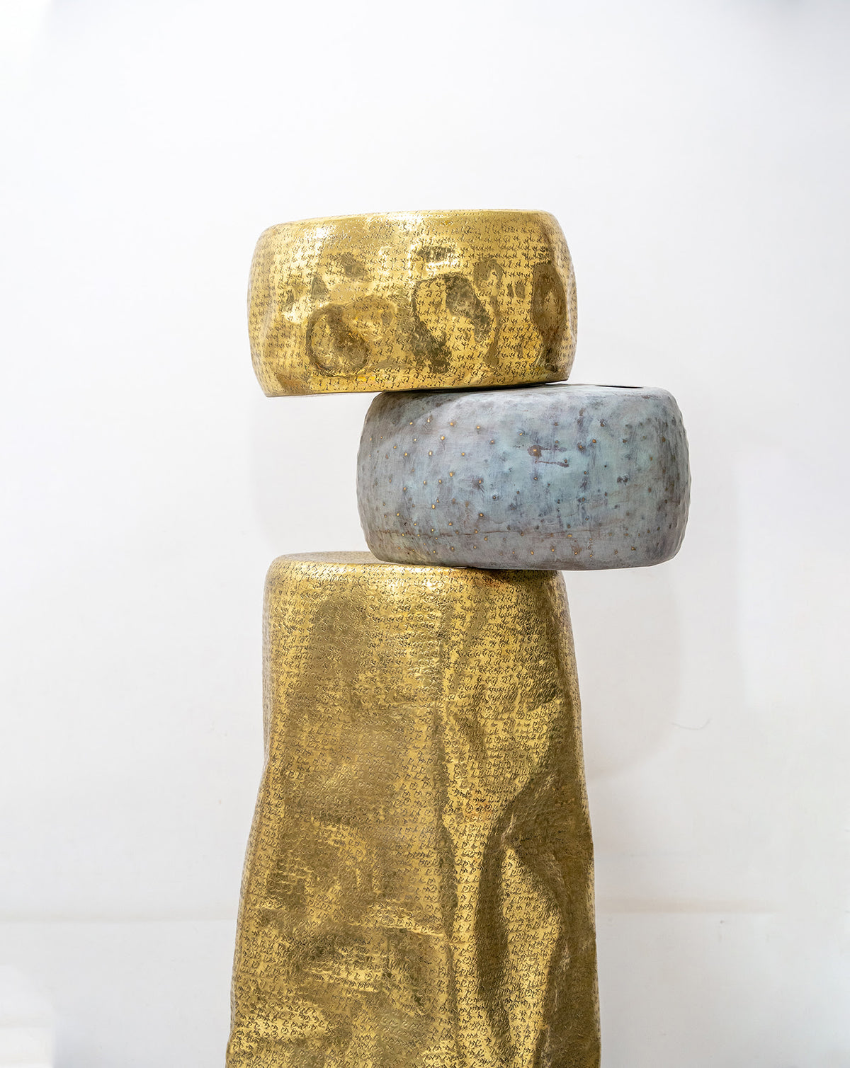 Slender branch-like detail extending from the upper section of the brass sculpture