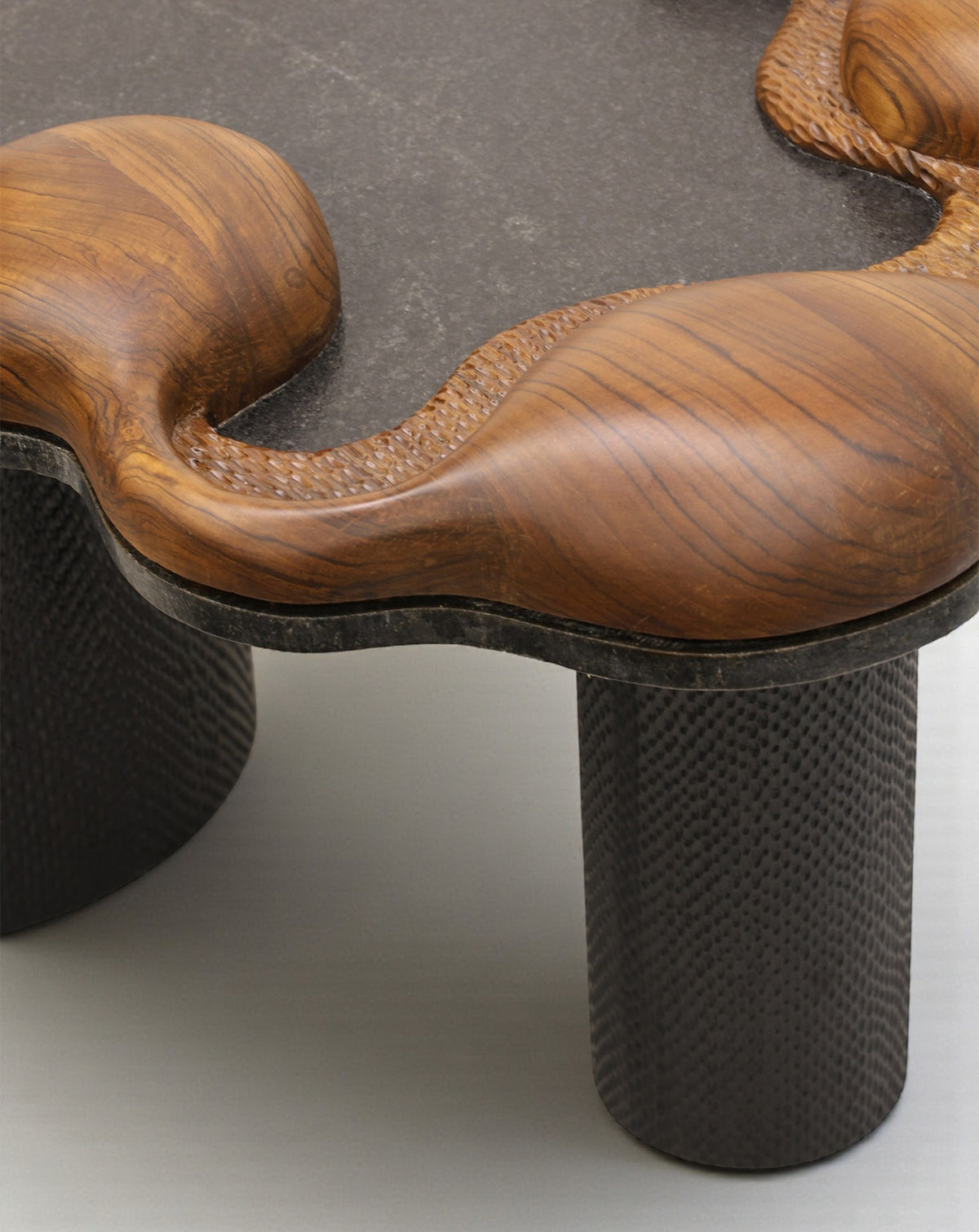 Handcrafted black granite tabletop paired with warm teak, in a serene, balanced composition