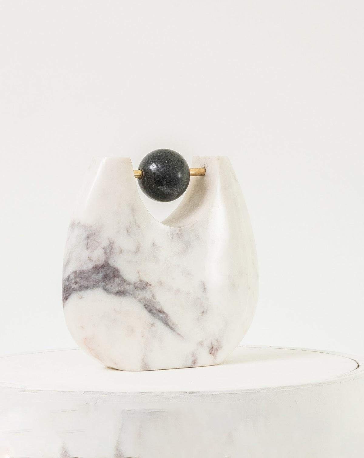 Polished black marble sphere suspended on a slender brass rod for contrast