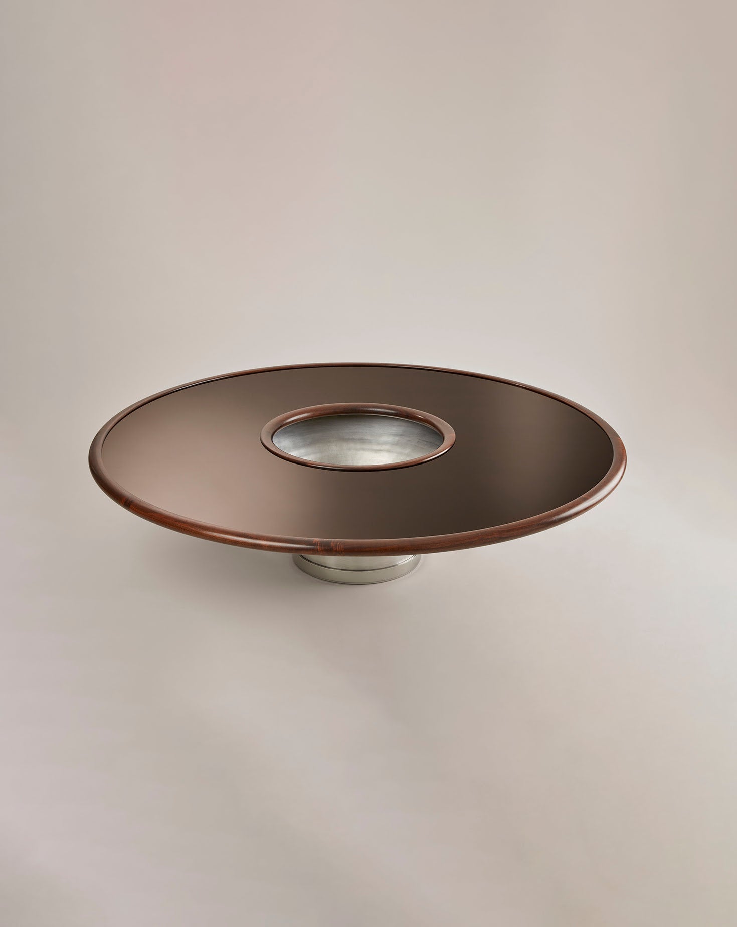 Round metallic object with a reflective surface on a beige background
