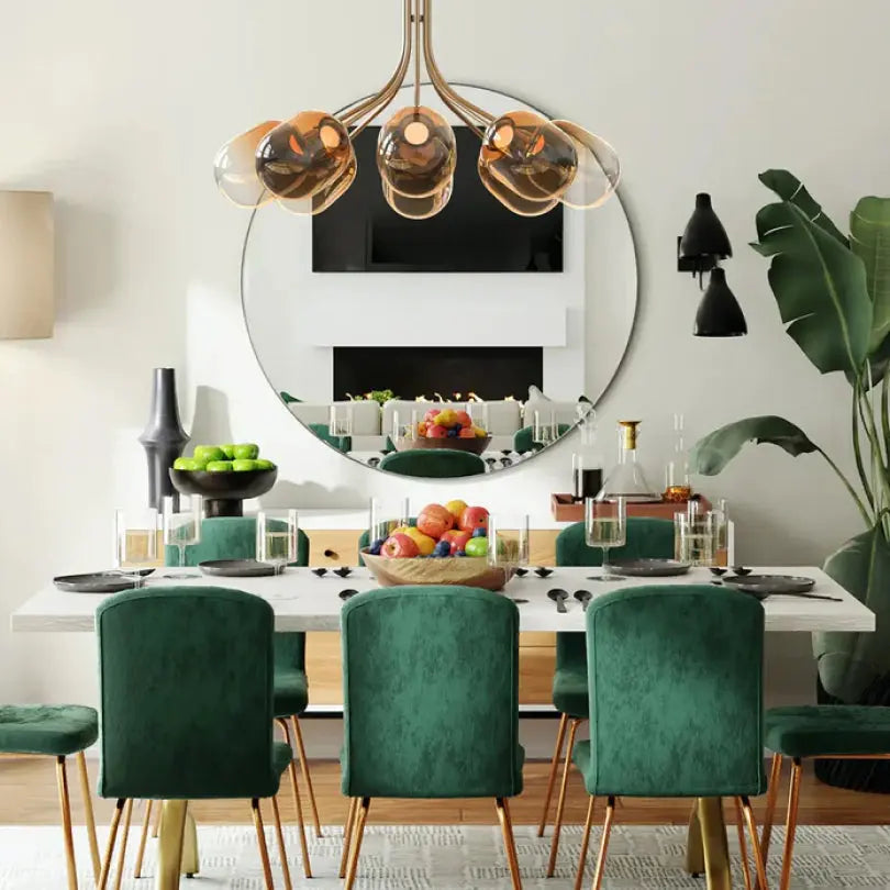 Dining room with green chairs, a white table, a large round mirror, and a decorative chandelier.