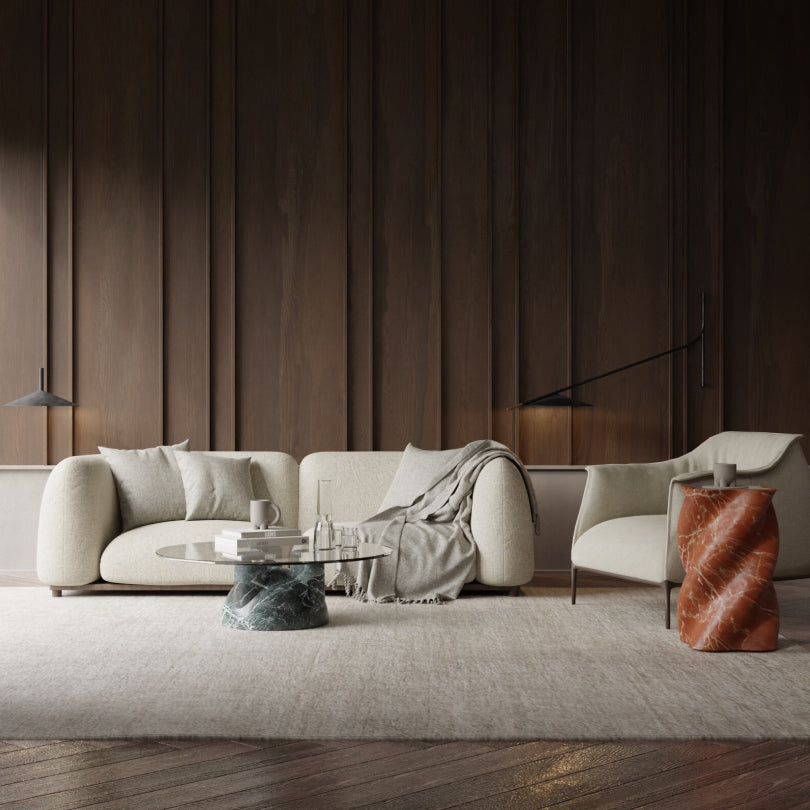 Modern living room with neutral-toned furniture, a marble coffee table, and dark wood-paneled walls.