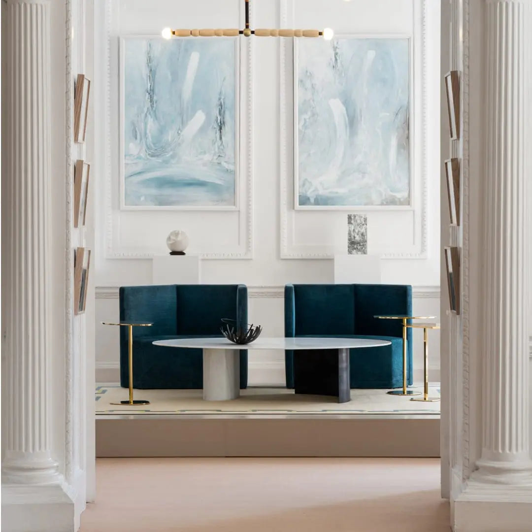 Interior of Nehru Centre in London’s Mayfair with blue seating, a round table, and abstract paintings on the wall.