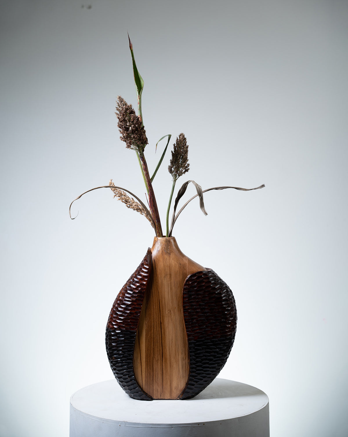 Tall tapering teak form rising with organic fluidity, carved by hand in India
