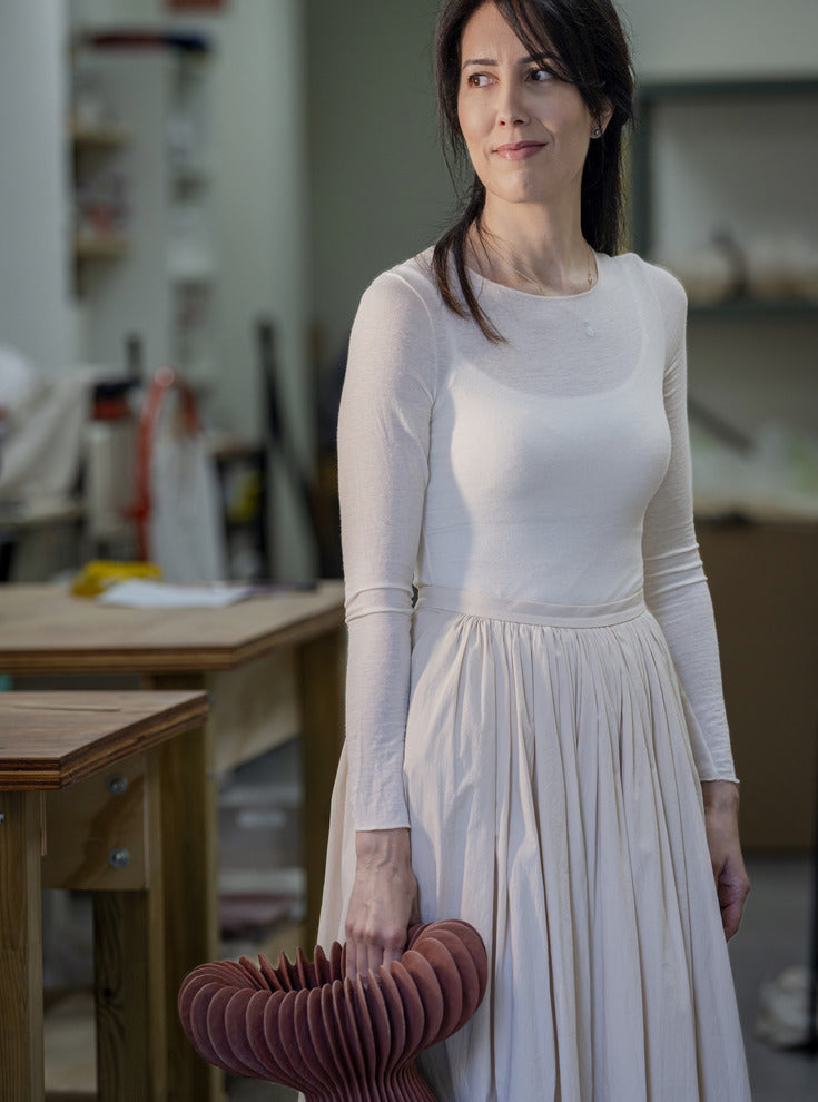Laura Ramírez holding a ribbed ceramic sculpture in her studio
