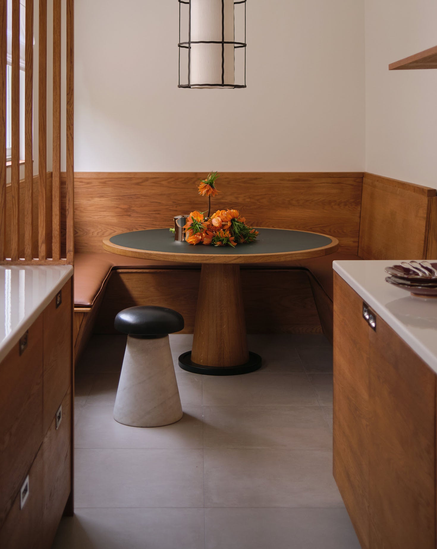 Modern interior with a round table, bench, and decorative flowers.