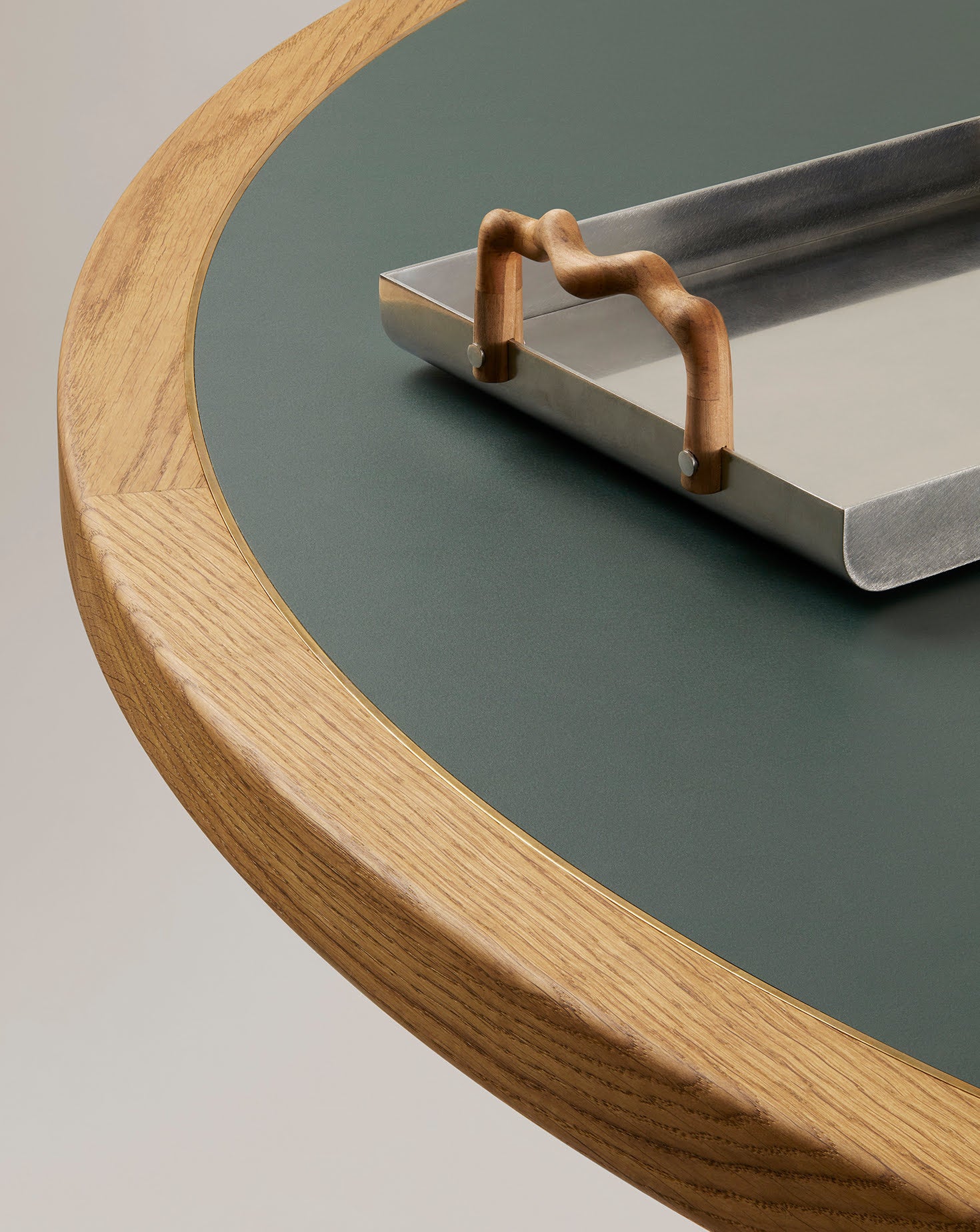 Metallic tray with a decorative handle on a round wooden table.